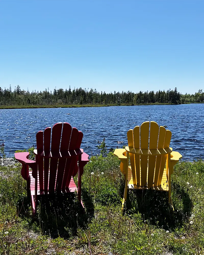 Two lounge chairs outside overlooking a lake at Shiraz Gardens in Hammonds Plains, Nova Scotia